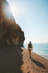 Wall Mural - Man tourist with backpack walking on empty beach traveling solo active vacations outdoor