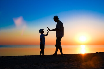 Wall Mural - A Happy parent with child by the sea play on nature silhouette travel