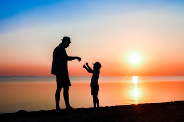 Wall Mural - A Happy parent with child by the sea play on nature silhouette travel