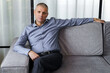 © Dzmitry - Handsome confident middle aged man is sitting on the couch
