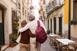 © Prostock-studio - Senior Couple Hugging Walking On Lisbon Street Outdoors, Back View