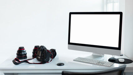 Wall Mural - Photographer workplace with blank screen computer monitor and camera accessories, white studio background, mockup