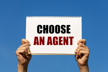 Choose an agent text on notebook paper held by 2 hands with isolated blue sky background. This message can be used as business concept about choosing agent.