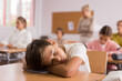 © JackF - Portrait of tired bored school boy lying and sleeping at desk in classroom during lesson
