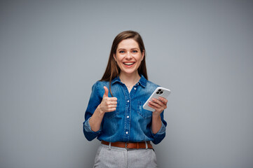 Poster - Woman using smartphone and showing thumb up. Portrait of smiling girl on gray back.