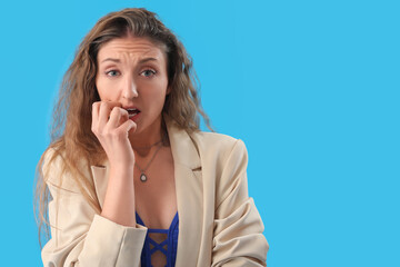 Sticker - Scared young woman in jacket on blue background, closeup