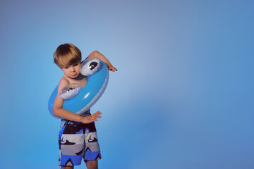 Happy cute boy 6 years old with a life buoy at the blue background