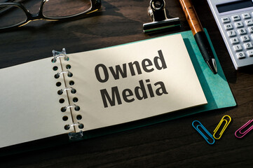 there is a notebook with the word owned media. it is eye-catching image.
