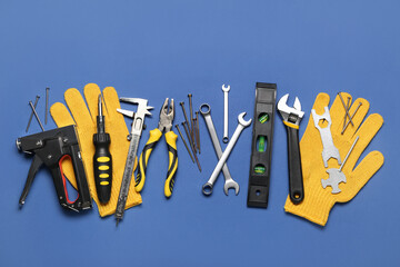 Wall Mural - Different construction tools and gloves on blue background