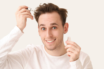 Wall Mural - Young man with serum for hair growth on white background, closeup