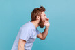 Side view of angry nervous bearded man loudly yelling widely opening mouth holding hands on face.