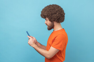 Wall Mural - side view of concentrated man writing post on social network using mobile phone.