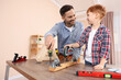 © New Africa - Father and son screwing wheels to wooden plank indoors. Repair work
