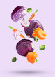 Many different fresh vegetables falling on pale light violet background