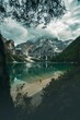 Breathtaking view of a person on the shor of a mountain lake under dense clouds in South Tyrol