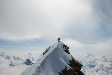 Wall Mural - Aerial view of snow covered mountain landscape with people standing on edge