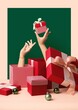 Vertical studio shot of hands coming out of gift boxes and holding another present, Christmas