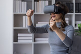 Fototapeta Sypialnia - Surprised Young latin woman in VR headset touching air, Smiling white woman wearing vr glasses while sitting on sofa at home.