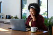 © WavebreakMediaMicro - Happy plus size african american woman sitting at table, making video call using laptop