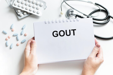 Wall Mural - White sticker with text Gout in doctor's hands with a stethoscope