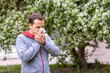 © Светлана Парникова - A man with an allergy or cold sneezes in a handkerchief against a flowering tree