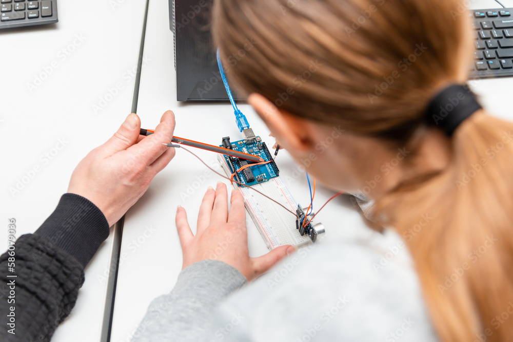Teacher helping his teen student with diy robot on stem education class ...