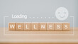 For wellness, wellbeing, relaxation mental health concept. wellness word on wooden cube block with loading and smiling face