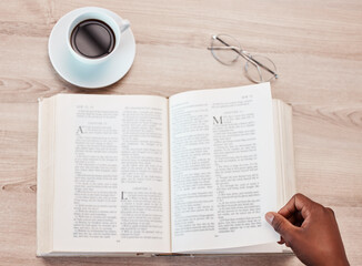 Hand, bible and a person reading in a coffee shop for religion, belief or faith in god and jesus. Education, learning and overhead with an adult in a cafe to study for spiritual knowledge in christ