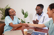 © Meeko Media - Two doctors shake hands while colleague claps, medical promotion achievement
