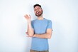 © Jihan - Overjoyed successful Young caucasian man wearing blue T-shirt over white background raises palm and closes eyes in joy being entertained by friends
