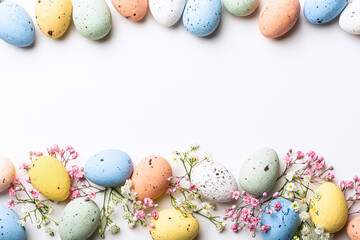 Wall Mural - Easter quail eggs and springtime flowers over white background. Spring holidays concept with copy space. Top view