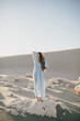 © polinaloves - Woman with long hair in a stylish dress poses in the desert sands.