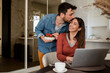 © Studio Dva Kera - Husband kisses his wife while she works from home as a freelancer.