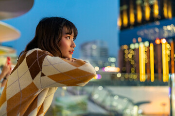 Wall Mural - Portrait of Young Asian woman looking cityscape building with street light during travel city street at night. Attractive girl enjoy and fun outdoor lifestyle shopping in the city on holiday vacation.