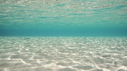 Wall Mural - Sandy shallow water in sunburst and glare on seabed sand, slow motion. Sunlight passes through surface of turquoise water and glares on sandy bottom in shallow water on bright sunny day