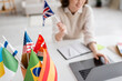 selective focus of international flags near teacher of foreign languages using laptop on blurred background.