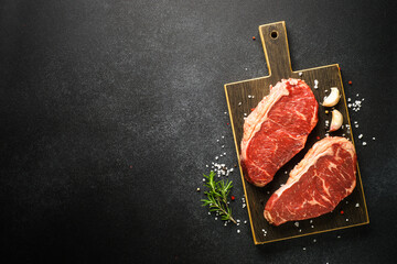 Wall Mural - Beef steak with spices. Raw beef meat at black. Top view with copy space.