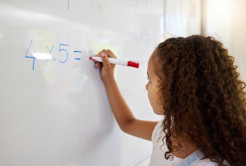 Whiteboard, math and girl writing for learning, studying and education in classroom. Development, mathematics and kid or student write equations, numbers and multiplication for knowledge in preschool