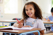 © Nina/peopleimages.com - Learning, drawing and portrait of girl in classroom exam, education or studying with book. Preschool smile, development and happy kid or student coloring for creative art in notebook in kindergarten.
