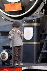 Wall Mural - Two boys, dressed in vintage clothing and hat, with suitcase, on a railway station