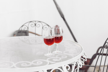 Two glasses of moscatel wine on a white metal table, white wall background 