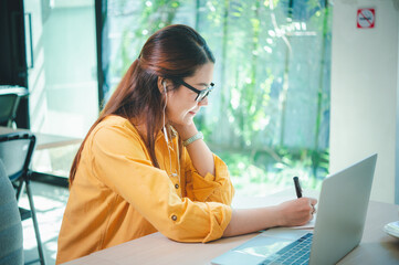 Wall Mural - business woman sits working online on a laptop computer in a cafe.