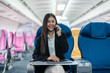 © Natee Meepian - attractive businessman in suit with talking on mobile phone and working on laptop while sitting in airplane cabin. Work and travel concept