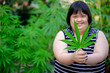 Woman with Down syndrome holding a marijuana leaf. She is mentally disabled standing with a marijuana plant.
