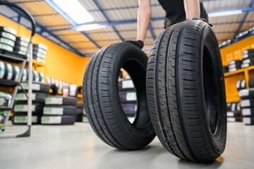 An auto mechanic at a garage or service center performing wheel changes brings new tires that are in stock in two lines to the tire shop.