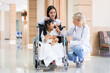 © ronnachaipark - Female pediatrician doctor and child patient on wheelchair with her mother in the health medical center