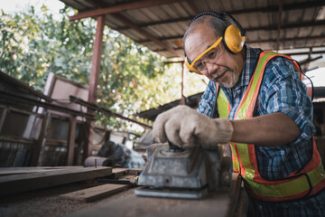 Wall Mural - An elderly carpenter works the wood with meticulous care.