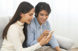 © KMPZZZ - Happy couple love at home,beautiful two asian young spending good time together,bonding to each other and smiling romantic on sofa in living room while man embrace woman using smartphone, mobile phone