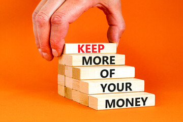 Keep more of your money symbol. Concept words Keep more of your money on wooden block. Beautiful orange table orange background. Businessman hand. Business keep more of your money concept. Copy space.