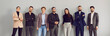 Happy smiling professional young business people, attractive men and women lined up along the wall, confidently looking at the camera. Panoramic shot on isolated gray background.